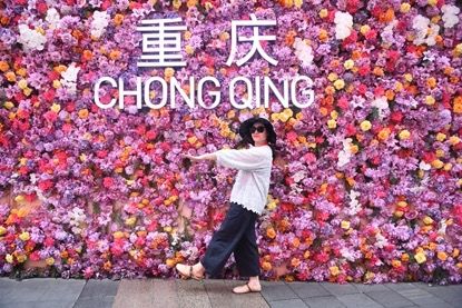 图为嘉宾在重庆观音桥商圈“鲜花墙”前打卡。 图为嘉宾在重庆观音桥商圈“鲜花墙”前打卡。